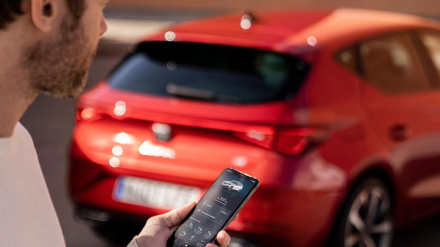 Mann steht vor einem SEAT und hält ein Smartphone in der Hand