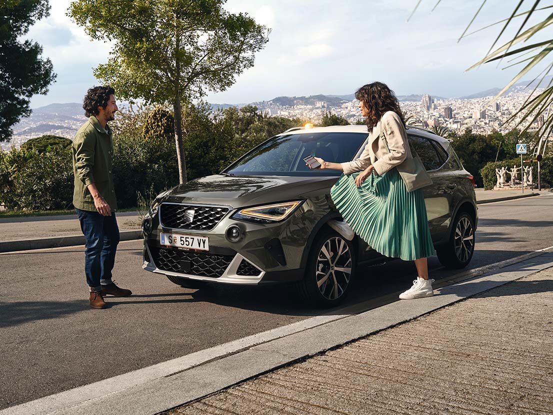 Ein Mann und eine Frau stehen neben einem SEAT Arona