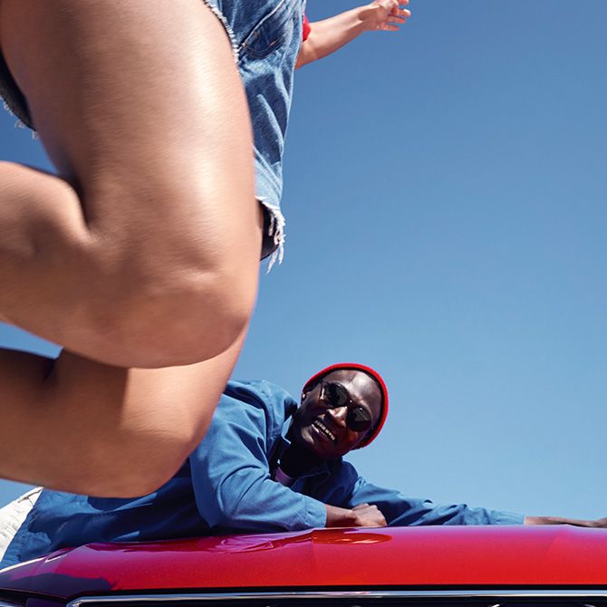 Ein Mann lehnt an der Motorhaube eines roten SEAT Ibiza.