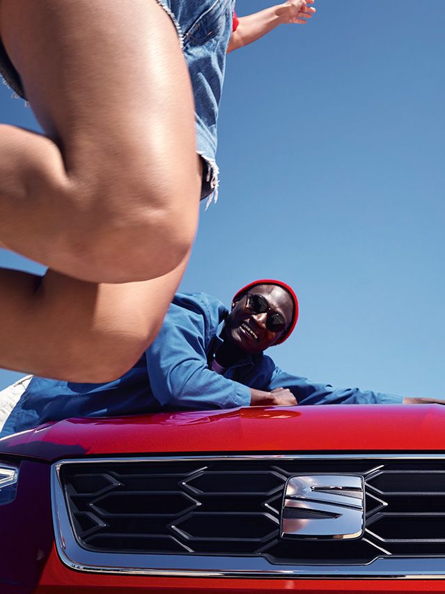 Ein Mann lehnt an der Motorhaube eines roten SEAT Ibiza.