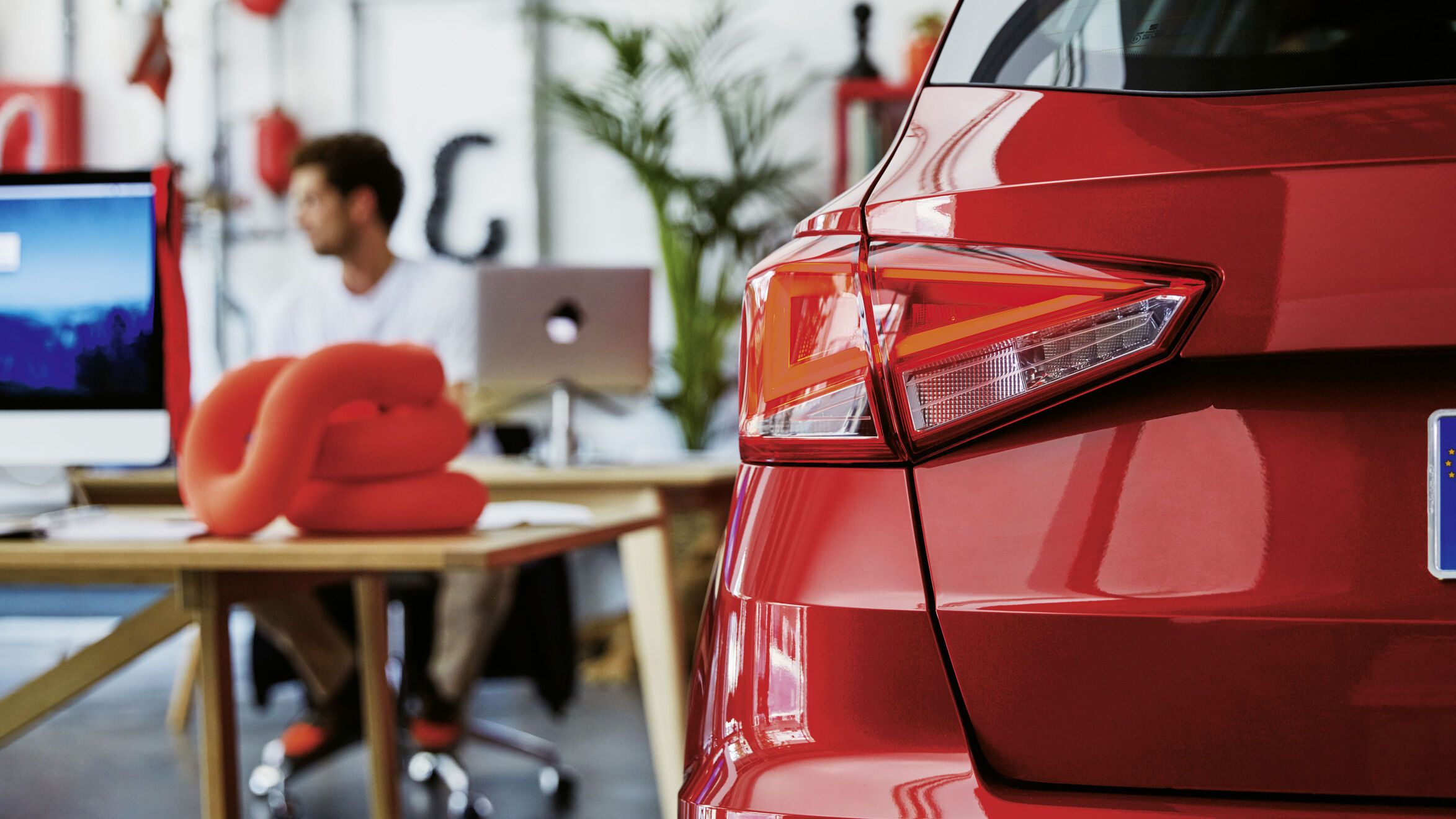 Der rote SEAT Arona ist in einem Büro positioniert und wird aus der Rückansicht gezeigt