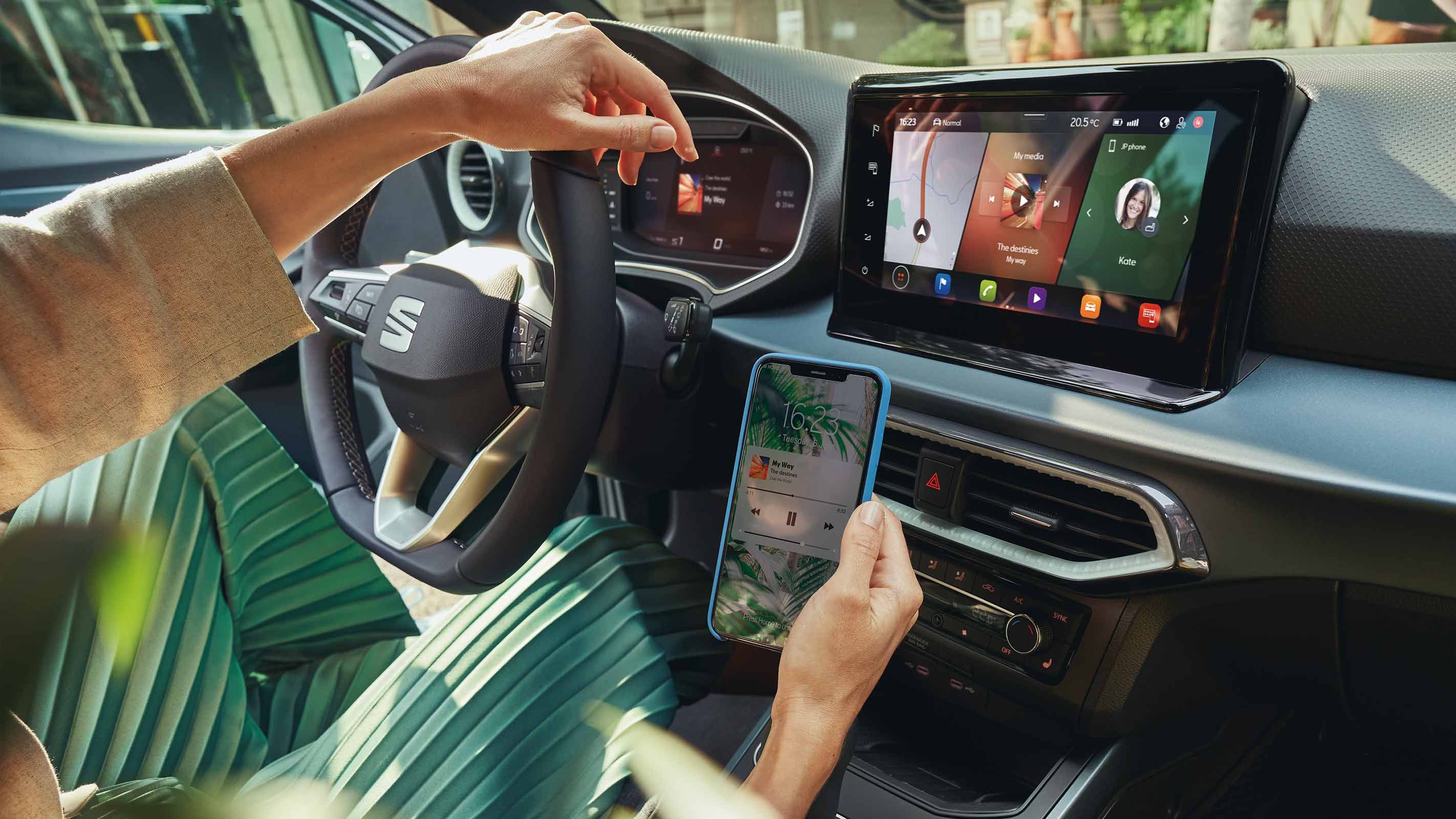 Eine Frau stellt die Verbindung zwischen ihrem Smartphone und dem Fahrzeug über Full Link her