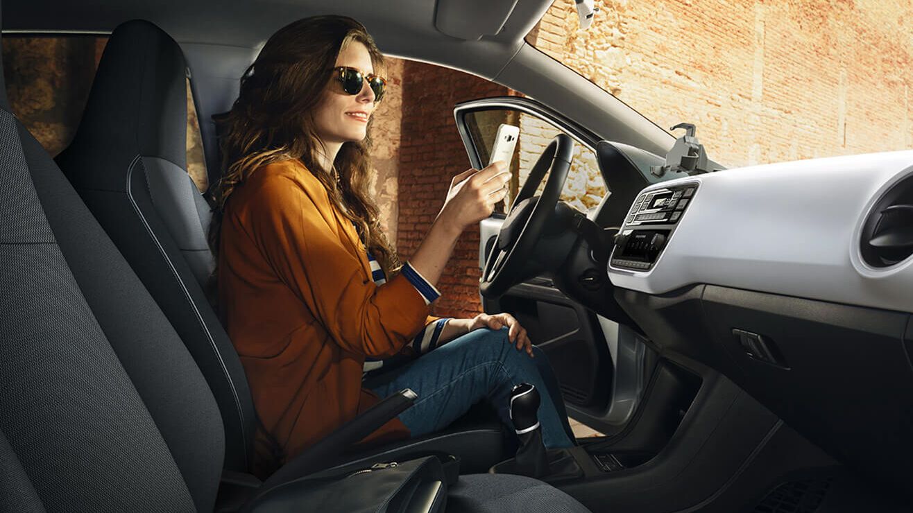 Frau mit Smartphone am Fahrersitz eines SEAT
