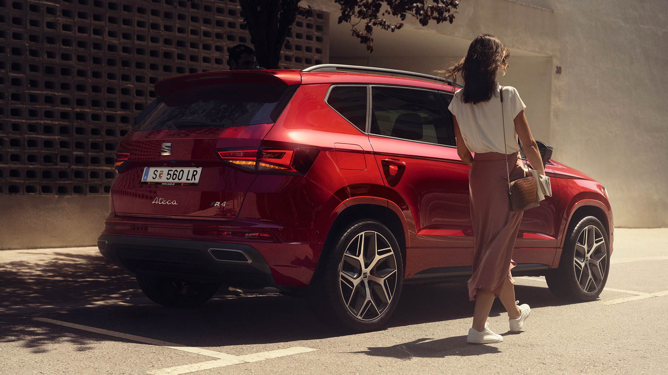 Eine Frau geht neben einem roten SEAT Ateca FR