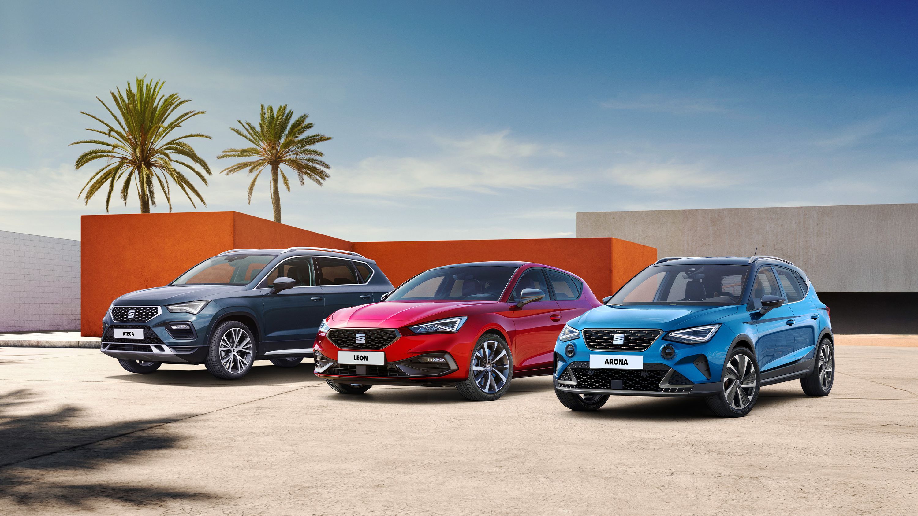 SEAT Arona, Leon a Ateca stoja pred modernou stavbou domu a v pozadí stoja dve palmy.